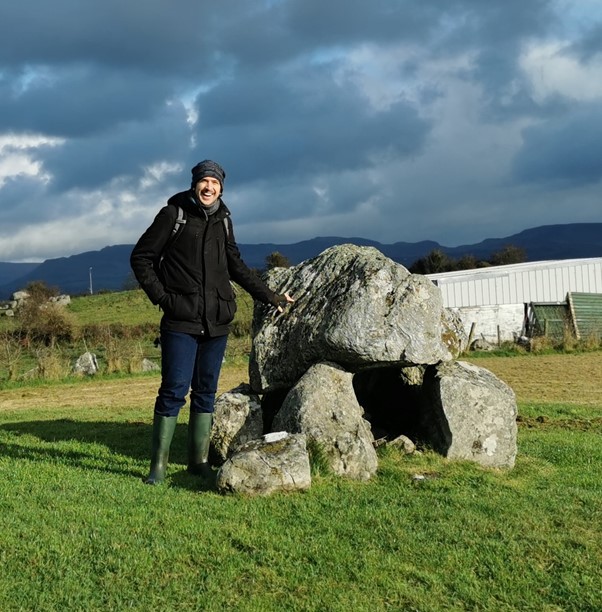 Image of person standing beside a rock.